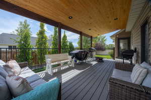 Wooden covered deck with outdoor lounge area and a grill