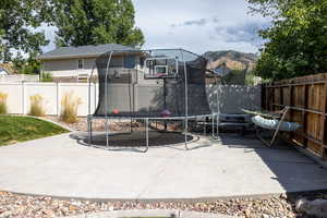 Fenced backyard with a trampoline and a patio area