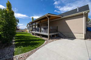 View of side of home featuring a shingled roof, a deck, and a patio area