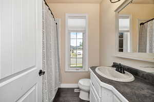Full bath with vanity, dark wood finished floors, and curtained shower
