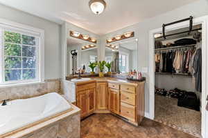Master bathroom featuring vanity, a garden tub, and a spacious closet