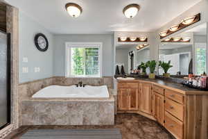 Master bathroom featuring double vanity, a garden tub, a shower stall, and dark tile patterned floors