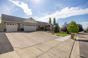 Ranch-style house featuring an attached garage, stone siding, driveway, roof with shingles, and a front yard