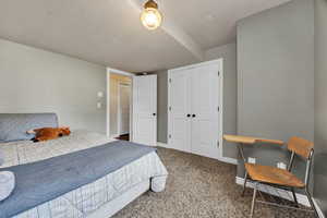 Bedroom 4 featuring a textured ceiling, dark colored carpet, and a closet
