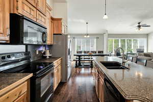 Kitchen featuring black appliances, pendant lighting, dark wood-style floors, open floor plan, and a ceiling fan