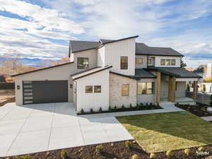 View of front facade with board and batten siding, covered porch, roof with shingles, and stone siding
