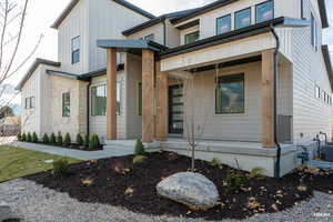 View of front of property with covered porch, stone siding, and board and batten siding