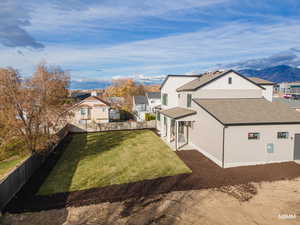 Rear view of house featuring a fenced backyard, a shingled roof, and a mountain view