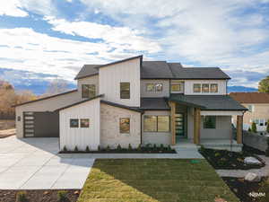 View of front facade featuring covered porch, roof with shingles, board and batten siding, stone siding, and a front yard