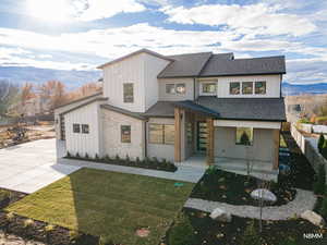 View of front of home featuring covered porch, roof with shingles, a fenced backyard, stone siding, and a mountain view