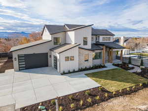 View of front of house featuring a shingled roof, board and batten siding, concrete driveway, a mountain view, and stone siding
