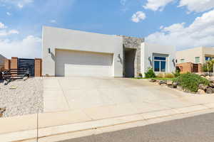 Modern home with stone siding, stucco siding, driveway, and a garage