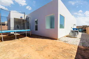 Back of house featuring a trampoline and stucco siding