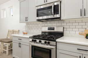 Kitchen featuring appliances with stainless steel finishes, light countertops, and white cabinets