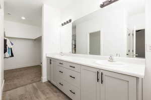 Full bath with a walk in closet, double vanity, light wood-style flooring, and recessed lighting