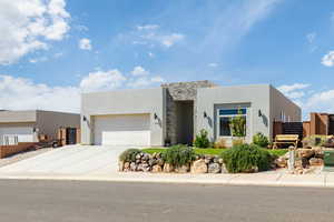 View of front of house with stone siding, stucco siding, concrete driveway, and a garage