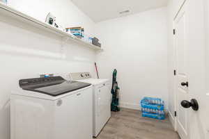 Laundry area featuring light wood-type flooring and independent washer and dryer