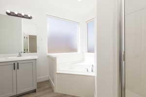 Bathroom featuring vanity, wood finished floors, and a garden tub