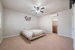 Bedroom featuring light carpet, a ceiling fan, a wall mounted AC, and ensuite bath