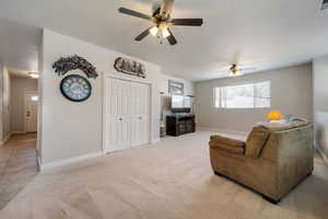 Living area featuring light carpet and ceiling fan