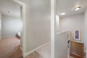 Hallway with light carpet and an upstairs landing