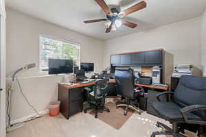 Home office with light carpet and ceiling fan