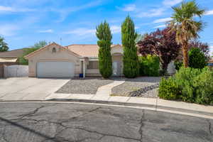 View of front facade with concrete driveway, a garage, stucco siding, a gate, and a tiled roof