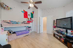 Bedroom with light wood-style flooring, ceiling fan, a closet, and a high ceiling