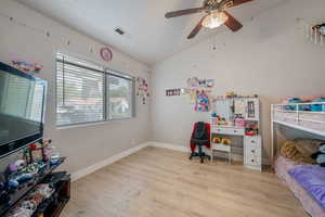 Bedroom with light wood-style flooring, lofted ceiling, and ceiling fan