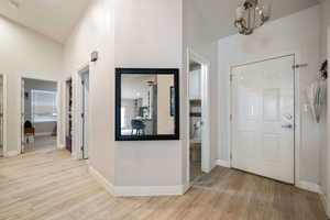 Foyer entrance with light wood-style floors and lofted ceiling