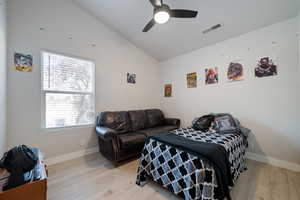 Bedroom with vaulted ceiling, light wood-style floors, and a ceiling fan