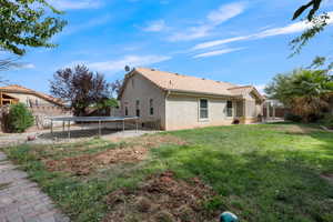 Rear view of property featuring a trampoline, stucco siding, a tiled roof, and a patio area
