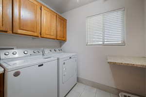 Laundry room featuring light tile patterned floors, cabinet space, and independent washer and dryer
