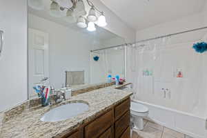 Bathroom featuring shower / bath combo with shower curtain, light tile patterned floors, and vanity