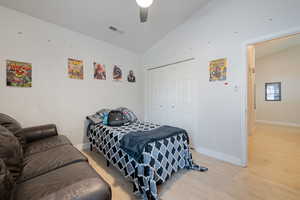 Bedroom with vaulted ceiling, light wood-style flooring, a closet, and ceiling fan