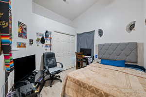 Bedroom with light wood-style flooring, a closet, and lofted ceiling