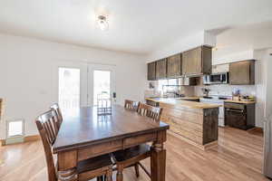 Kitchen featuring a peninsula, light countertops, appliances with stainless steel finishes, decorative backsplash, and dark brown cabinetry