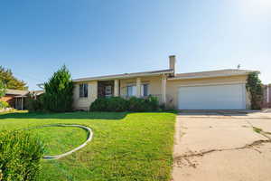 Single story home with brick siding, concrete driveway, a porch, a front yard, and an attached garage