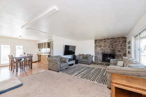 Living area featuring a textured ceiling, a fireplace, light colored carpet, and light wood-style flooring