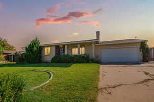 View of front of property with concrete driveway, a garage, brick siding, a front yard, and covered porch