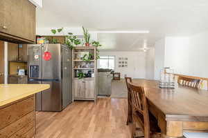 Kitchen with stainless steel fridge with ice dispenser, light countertops, light wood-type flooring, and a textured ceiling