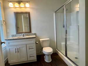 Full bathroom with vanity, a stall shower, and dark wood finished floors