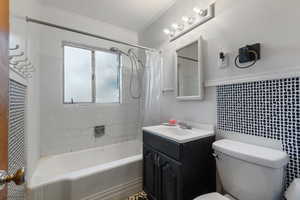 Bathroom featuring shower / bath combination with curtain, vanity, crown molding, and tasteful backsplash