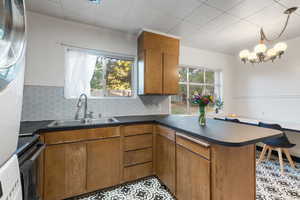 Kitchen with tasteful backsplash, dark countertops, brown cabinetry, a peninsula, and ornamental molding