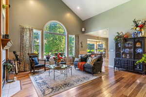 Living room featuring high vaulted ceiling, a fireplace, hardwood / wood-style flooring, and recessed lighting