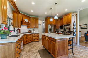 Kitchen with brown cabinets, a breakfast bar area, a center island with sink, and recessed lighting