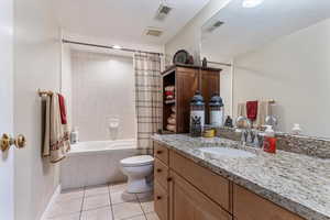 Bathroom with tiled shower / bath, vanity, and light tile patterned floors