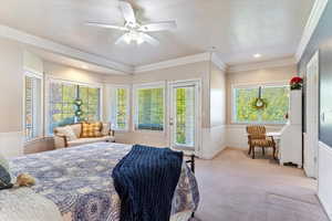 Carpeted bedroom with ornamental molding, access to exterior, ceiling fan, a textured ceiling, and wainscoting