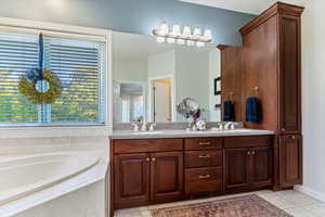 Bathroom with double vanity, a bath, and light tile patterned floors