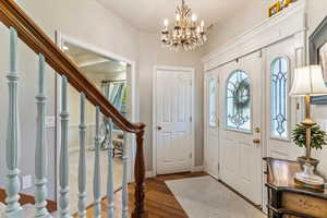 Foyer with stairs, wood finished floors, and a chandelier